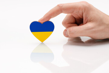 Love and respect Ukraine. A man's hand holds a heart in the shape of the Ukrainian flag on a white...