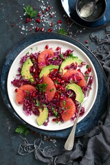 Red cabbage salad with avocado, grapefruit and pomegranate. Diet food. Top view with copy space.