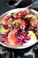 Red cabbage salad with avocado, grapefruit and pomegranate. Diet food. Top view with copy space.