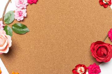 Frame made of rose flowers on cork board  background. Top view with copy space.