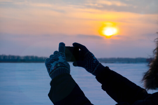 Silhouette of a person taking a picture of the sun. Winter.