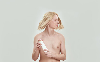 Obraz premium Young man shaking long hair and holding shampoo