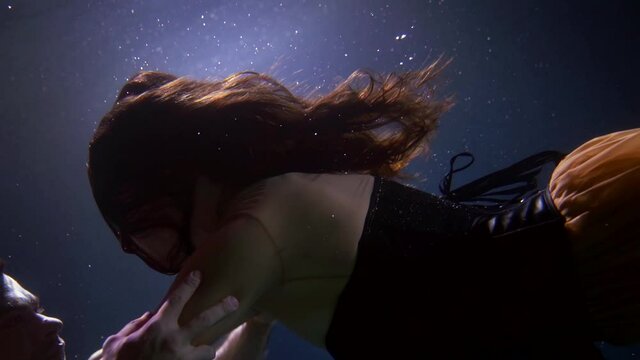 romantic date underwater, loving couple are swimming in dark water of sea or ocean