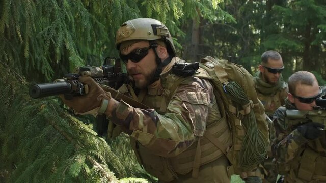 Medium closeup of squad of special forces with rifles on secret operation in jungle, investigating territory