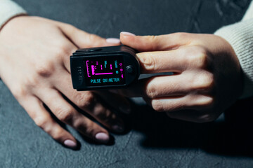Measuring amount of oxygen in blood with pulse oximeter. Saturation and pulse checking at home, fast diagnostics of Covid-19. Close-up monitor view.