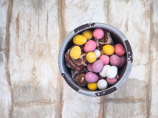 Easter sweets, chocolate eggs and dried persimmon in a gray ceramic jar on a light background