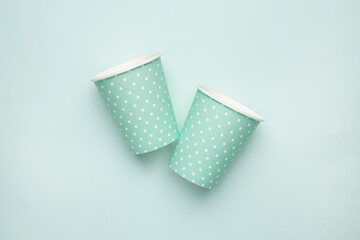 Paper cup with polka dot print green color on mint background. Eco friendly takeout cup for drink
