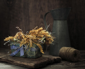 Still life with a bouquet of wheat ears and lavender in a metal pot on a wooden table.