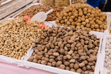 Street counter with nuts in shell: almonds, pecans, walnuts.