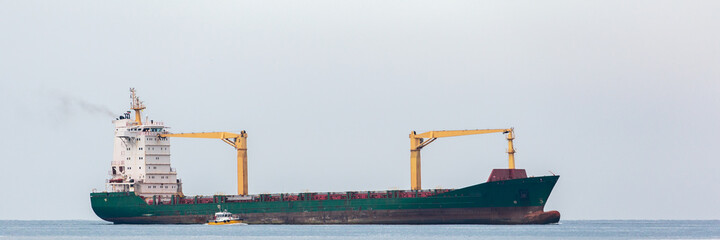 container ship being maneuvered by a tugboat