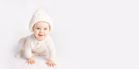 baby crawls in a warm suit and hat on a white isolated background, space for text, banner