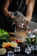 A man cook holds a trout in a vacuum package.