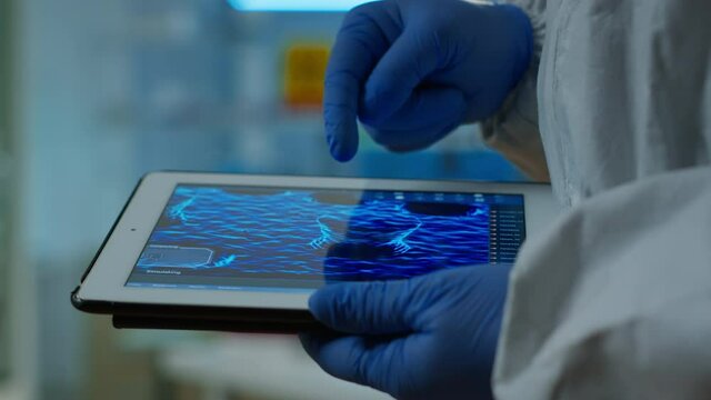 Close up of chemist doctor working on tablet with DNA scan image analysing treatment results. Scientist examining virus evolution using high tech researching vaccine development against covid19