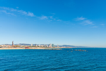 Fototapeta na wymiar BARCELONA, SPAIN, FEBRUARY 3, 2021: Barcelona coast a sunny winter day. During the covid-19 pandemic. View from inside the water. In the background we can see the new modernist buildings on the coast.