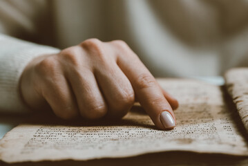 Woman reading ancient book - Bible. Concentrated attentively follows finger on paper page in library. Old archival manuscripts. History concept.