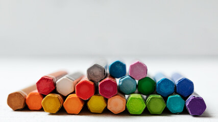 colored crayons for drawing on a white wooden background. a set for a young artist. the concept of creativity. side view. selective focus