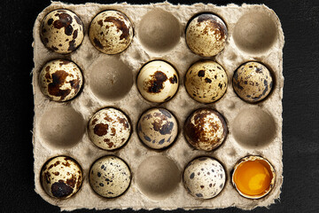 Quail eggs in the cardboard packing on the grey scratched table.