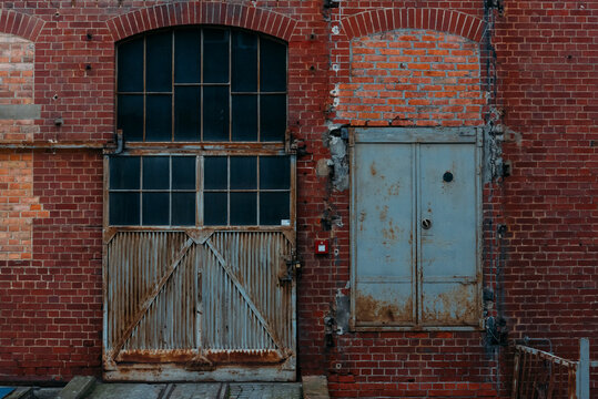 An old rusty gate of an old warehouse, old brick warehouse, brick facade and an old gate