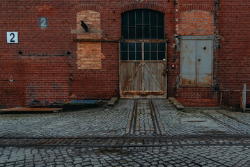 An old rusty gate of an old warehouse, old brick warehouse, brick facade and an old gate