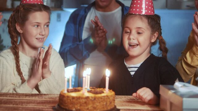 kid birthday. little girl blows out the candles on the cake in a circle of happy family. celebration birthday kid concept. friendly happy family dream celebrating birthday a lot of people