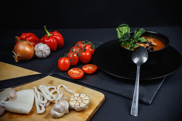 Soup with seafood and vegetables. Still life on a dark background.