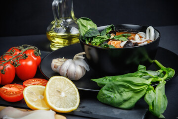 Soup with seafood and vegetables. Still life on a dark background.