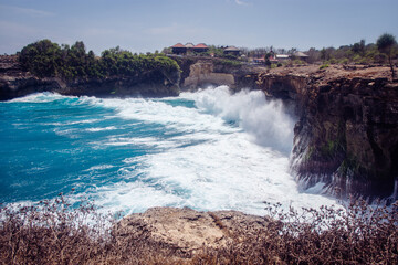 The wild sea creates high waves that hit the rocks at The Old Tree, Nusa Ceningan. Part of Nusa Lembongan, Bali, Indonesia.