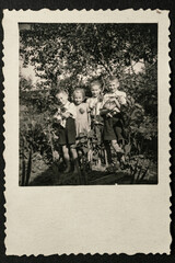 Germany - CIRCA 1930s: Group photo of four small kids standing and holding cats in garden. Vintage archive Art Deco era photography