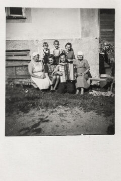 Latvia - CIRCA 1930s: A family group shot in porch outdoor. Man with accordions.Vintage art deco era photo