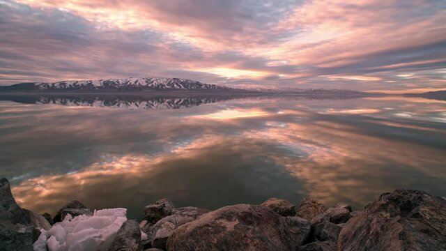 Reflection of clouds moving over the surface of Utah Lake in timelapse during sunset viewing the pattern and texture of the sky.