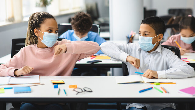 Diverse Pupils Wearing Surgical Face Masks Greeting And Bumping Elbows