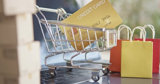 Online shopping, e-commerce and delivery service concept : Credit card in a cart or trolley, paper shopping bags on a laptop computer, depicts buyer order or buy goods from retailer sites via internet