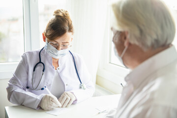 Doctor fills in coronavirus vaccination card for senior man patient during Covid-19 pandemic. The concept of defeating Covid-19