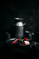 Black pasta with tomatoes and parmesan in a black plate