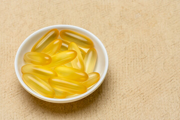 cod liver oil - dietary supplement, a bowl of capsules with a copy space, healthy eating concept