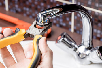 plumbing faucet repair concept. plumber using wrench tool and pliers to adjusting tap leak at...