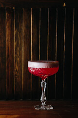 Red cocktail in glass on a wooden stand