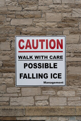 Fototapeta na wymiar Caution possible Falling ice red and white sign on stone wall