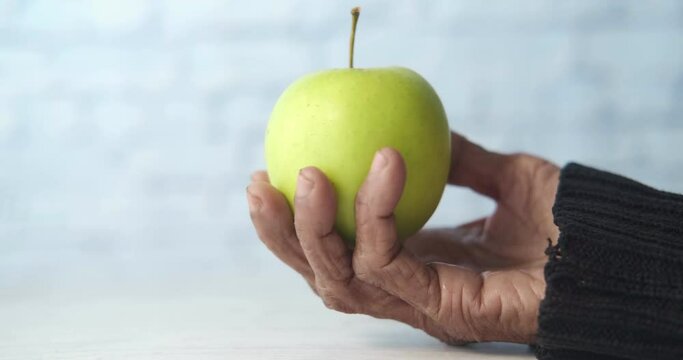 senior women hand holding green apple on white background 