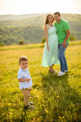 Fototapeta premium Young family with cute little boy having fun outdoors in the field
