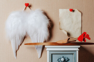 Angel wings hanging on the wall . Cupid weapons set bow and arrows on the nightstand. Valentines...