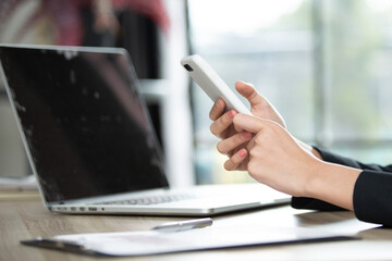 Businessman hands using smartphone and Computer notebook at the office desk. Blank screen mobile phone for graphic display montage