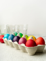 Colored Easter eggs in carton box on kitchen counter