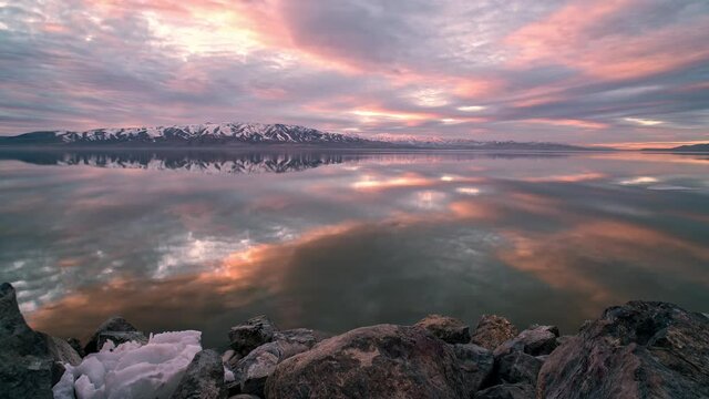 Colorful sunset time lapse of ice floating on Utah Lake reflecting the sky as the weather warms and melts the snow and ice.
