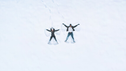 Happy young couple making snow angels. High angle. High quality photo