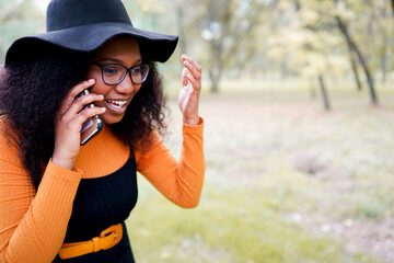 Black woman talking on phone outdoors in the park