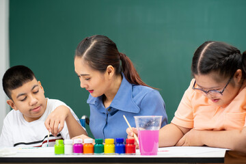 Asian disability boy learning color Painting in classroom with Autism girl in special school with female teacher.