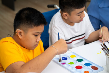 Asian disability boy learning color Painting in classroom with Autism girl in special school with female teacher.