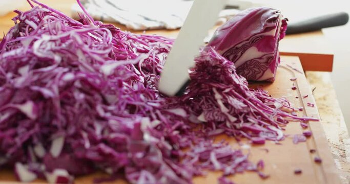 Red cabbage cut into thin slices using kitchen mandoline slicer, sauerkraut making process, close up