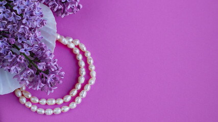 lilac flowers with pearl necklace on lilac background